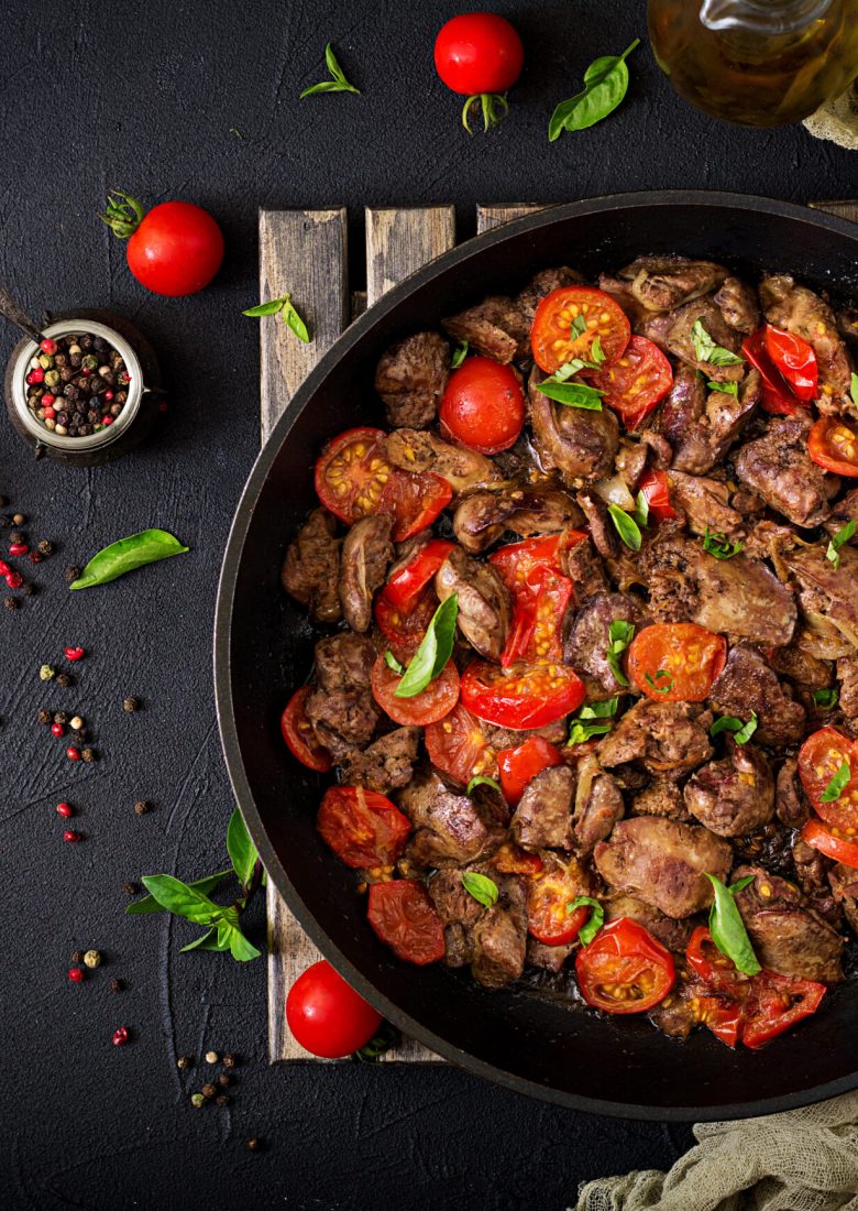 Chicken liver (offal) with onions and tomatoes in a frying pan in Armenian. Flat lay. Top view