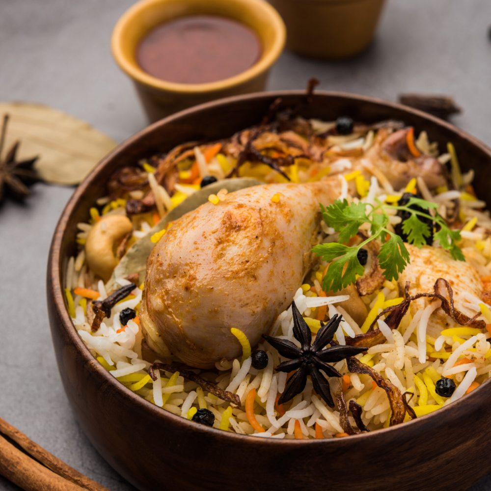 Restaurant style Spicy Chicken Biryani in wooden bowl with Raita and salan, Popular Indian or Pakistani Food
