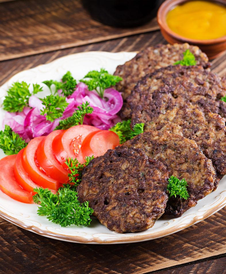 Chicken liver pancakes with vegetables  on wooden background. Fried chicken liver fritters idea. Rustic style.