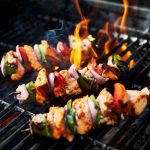 grilling chicken kabobs on flaming grill